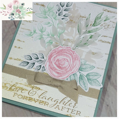 Soft green card base with hand stamped wood background on white, multiple shades of green and mauve die cuts of leaves and berries, pink raised rose die cut, tan ribbon, hand stamped love & laughter forever after in brown ink.